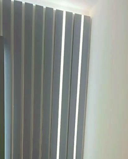 Grey fluted panels with recessed vertical LED strips and a lit ceiling cove
